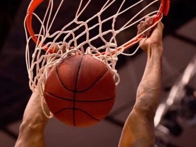 A basketball is in the air with its hands on a hoop.