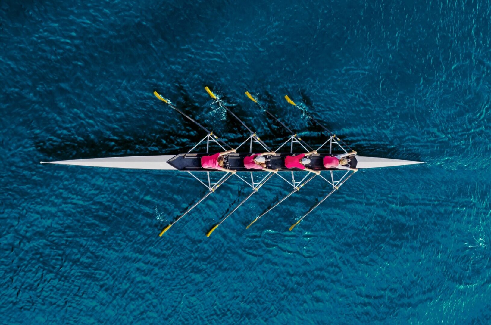 Four people rowing a boat in the water.